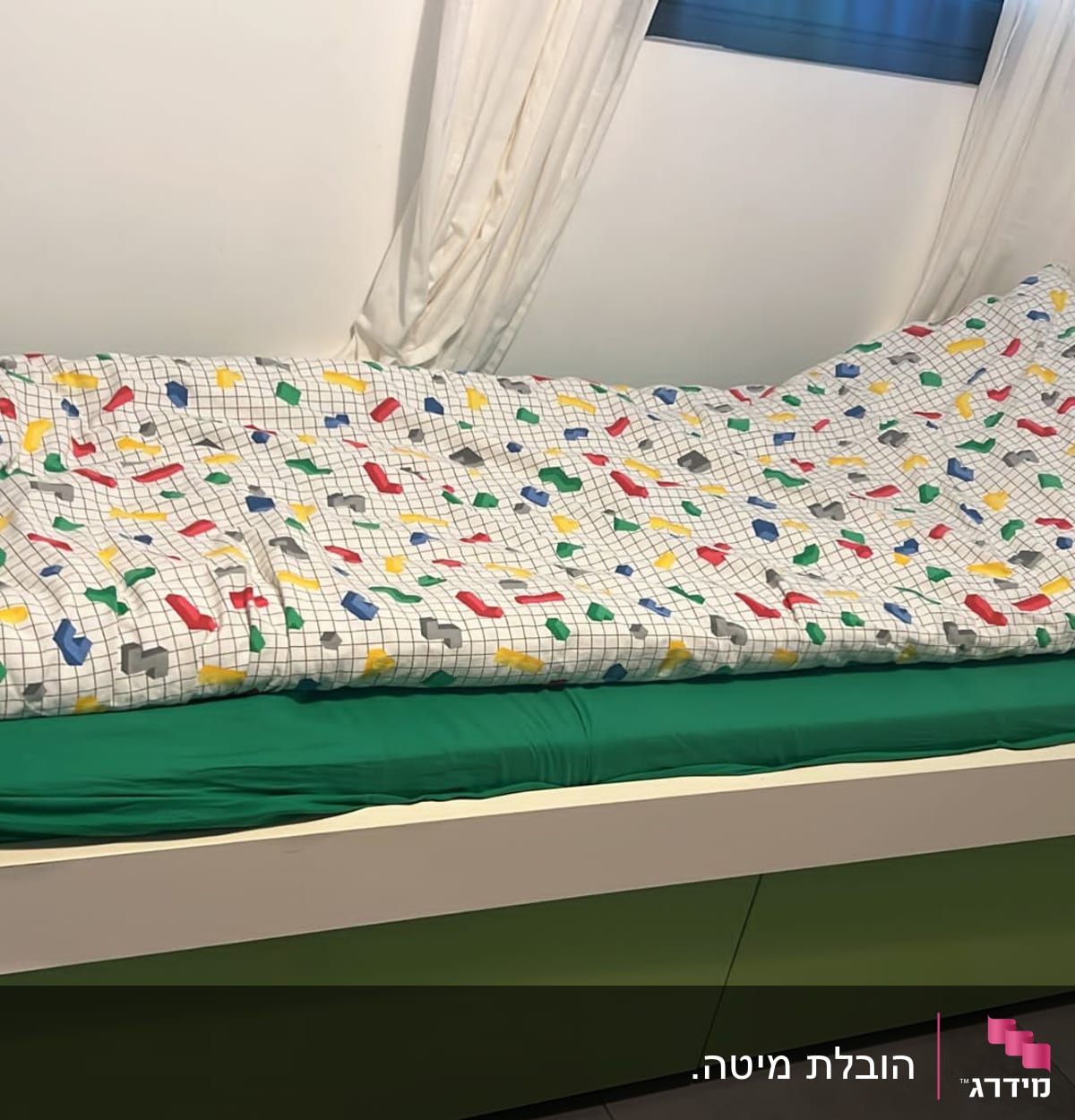 מיטה עם מצעים צבעוניים על רקע קיר לבן